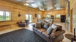 A spacious living area with a leather sofa, a dining table, and a kitchen in the background. - Burkesville Cabin, 3 Mi to Dale Hollow Lake! (Burkesville)
