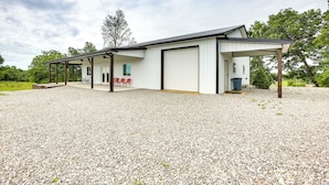 A modern building with a covered patio, a garage, and a gravel driveway. - Burkesville Cabin, 3 Mi to Dale Hollow Lake! (Burkesville)