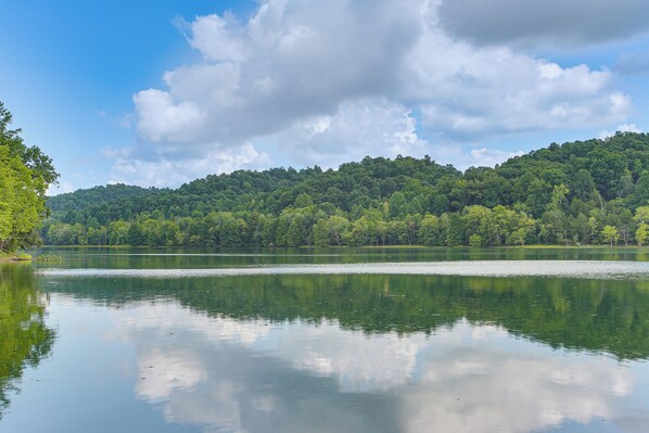 Un lac paisible, avec une colline boisée en arrière-plan.