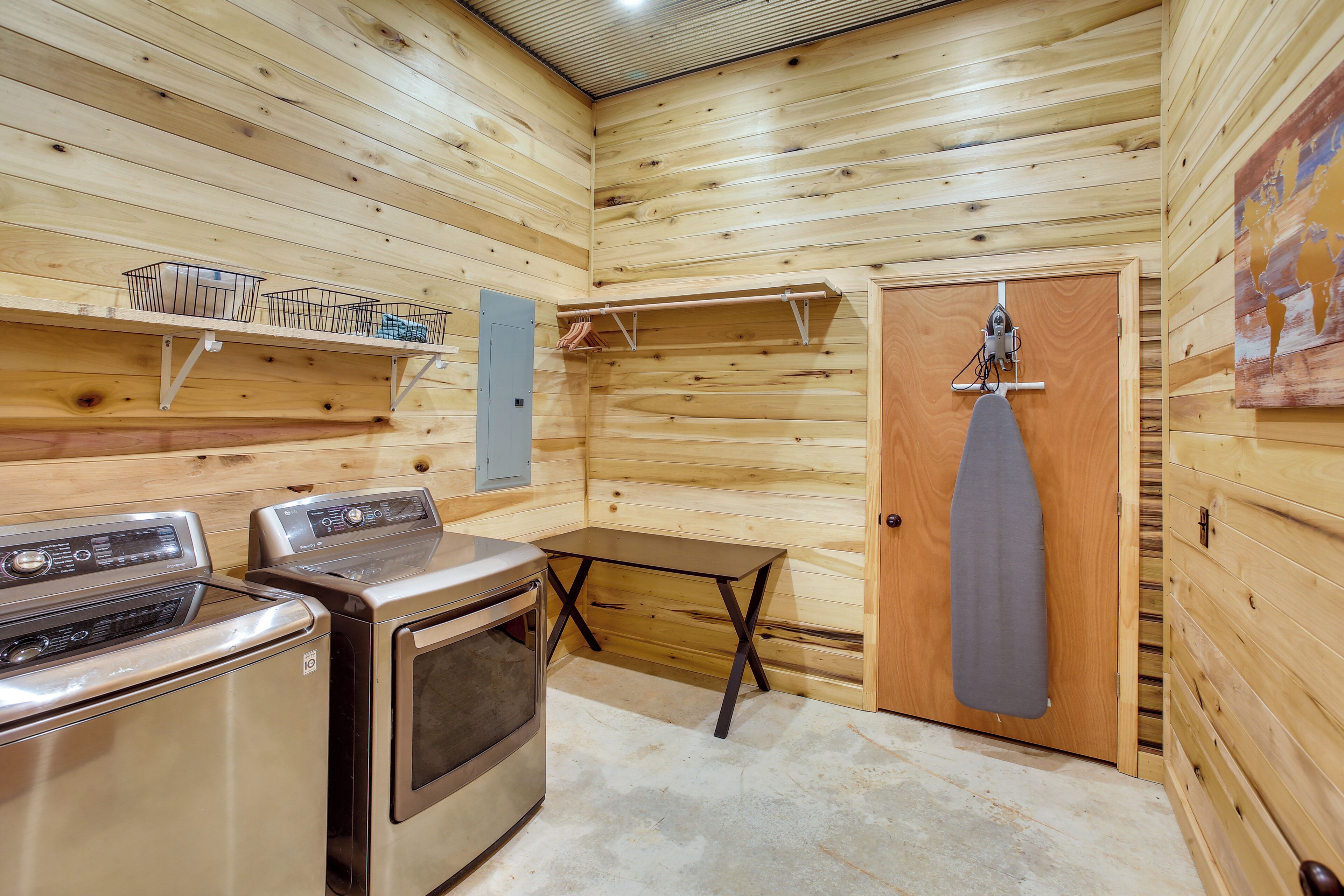 A compact kitchen with a stove, two dryers, a small table, and a drying rack.