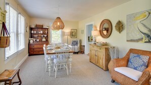 A dining area with a table set for four, a wicker sofa, and a wooden cabinet. - Mobjack Bay Rental on Private Cove! (Bohannon)