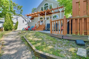 A house with a wooden deck, a covered porch, and a backyard with a gravel path and grass. - Turtle Cove Bay Beach House ~ 13 Mi to Buffalo! (Lake View)