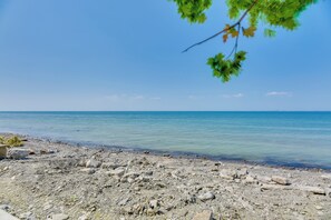 A rocky beach with clear blue water and a distant horizon. - Turtle Cove Bay Beach House ~ 13 Mi to Buffalo! (Lake View)
