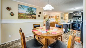 Comedor con mesa de madera, sillas y lámpara colgante.