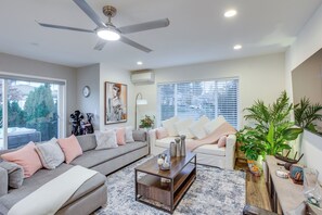 A modern living room with a grey sectional sofa, a coffee table, and a ceiling fan. - Newly Built Maple Valley Vacation Rental w/ Patio! (Maple Valley)