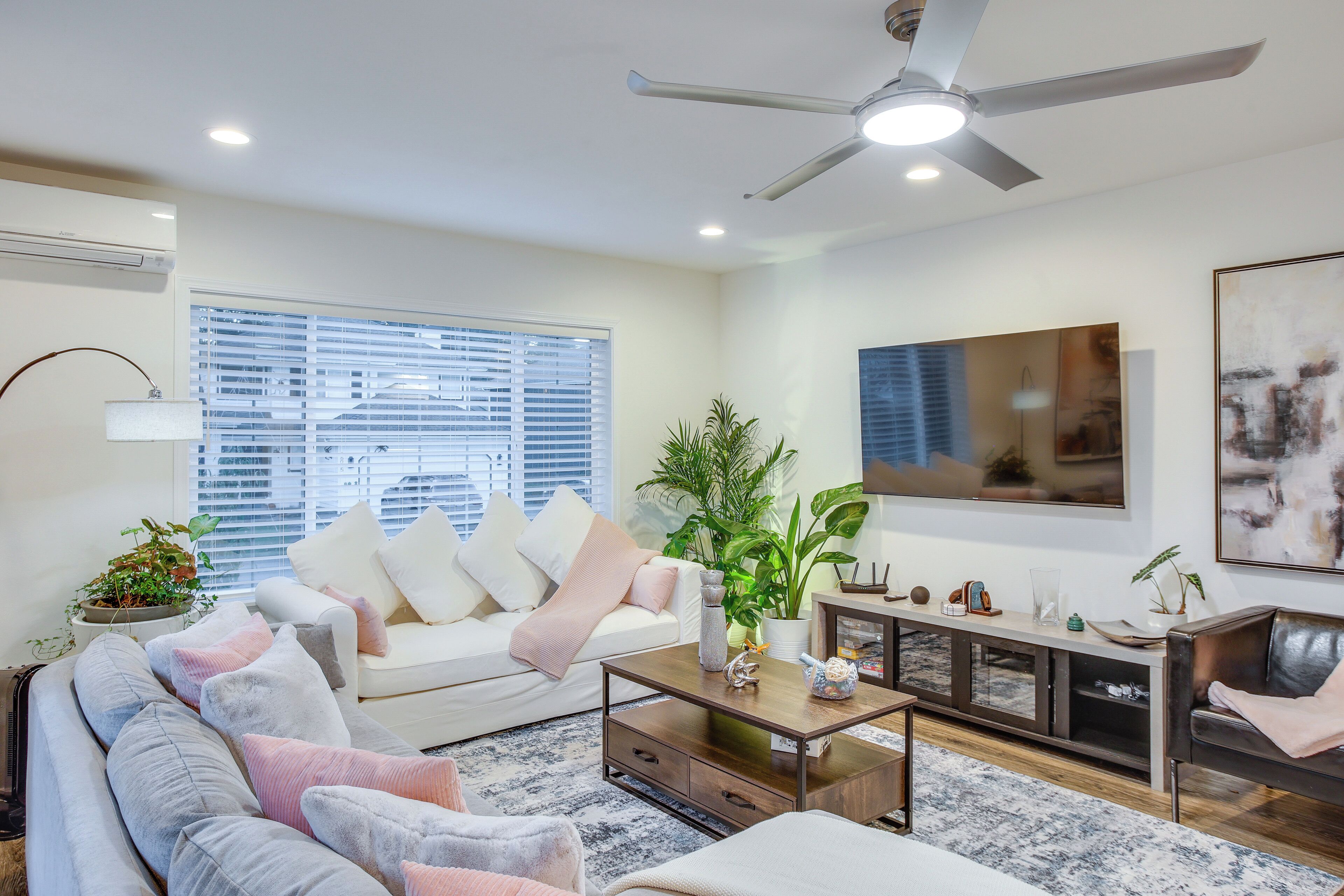 Una sala de estar moderna con un sofá, una mesa de centro y un televisor montado en la pared.