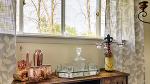Un coin bar en bois avec des chopes en cuivre, une carafe en cristal et des verres disposés sur un plateau.
