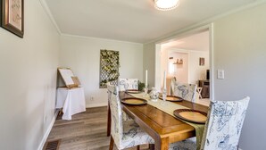 Une salle à manger avec une table en bois dressée pour quatre personnes, entourée de chaises à motifs.