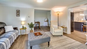 Un salon moderne comprenant un canapé, un pouf et un coin repas avec une table et des chaises.