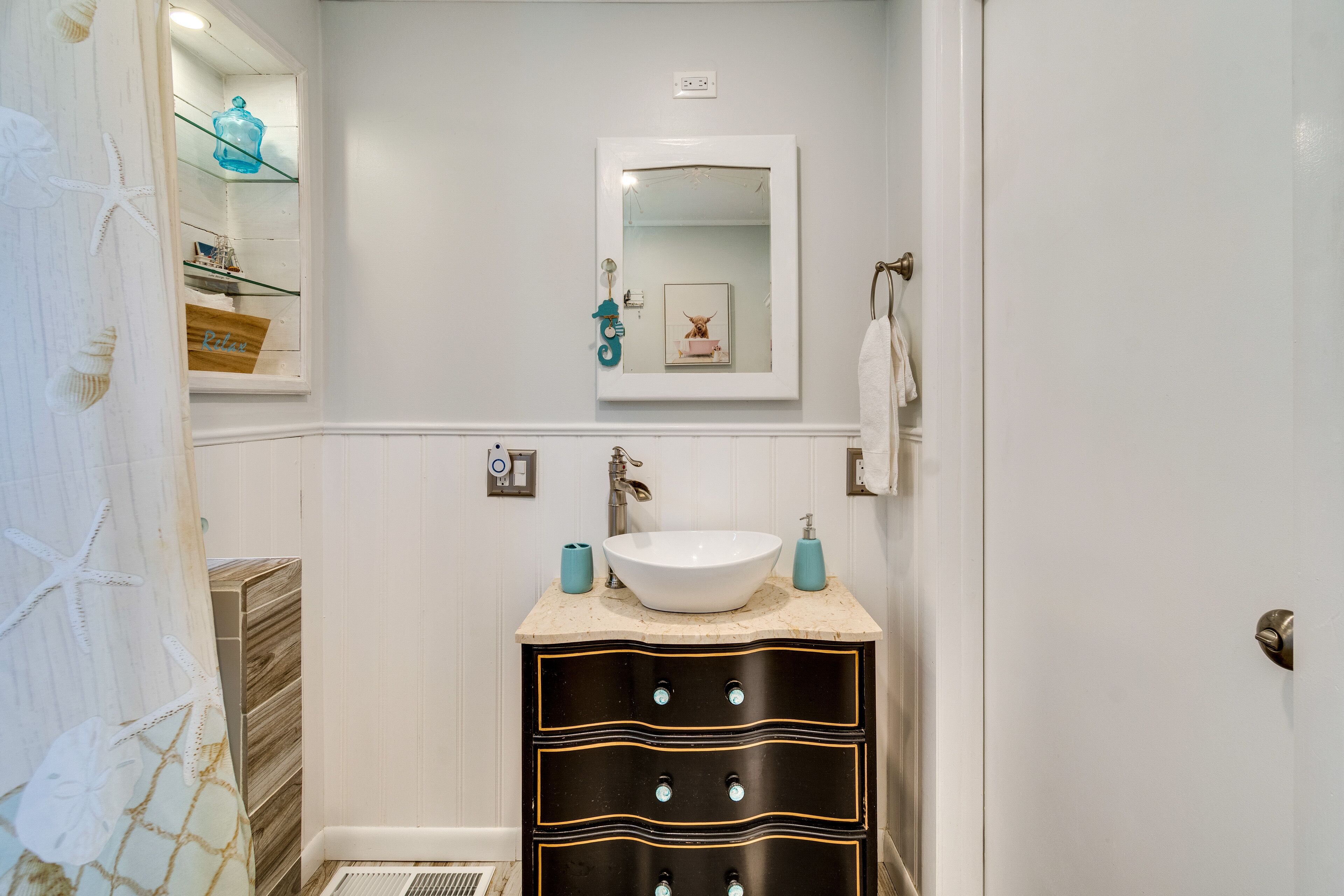 A bathroom with a white sink, a mirror, and a vanity with drawers.