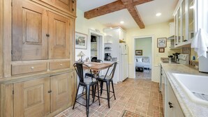 A kitchen with wooden cabinets, a dining table with chairs, and a tiled floor.