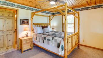 A wooden four-poster bed with a quilt, a nightstand with a lamp, and a door with a wooden frame.