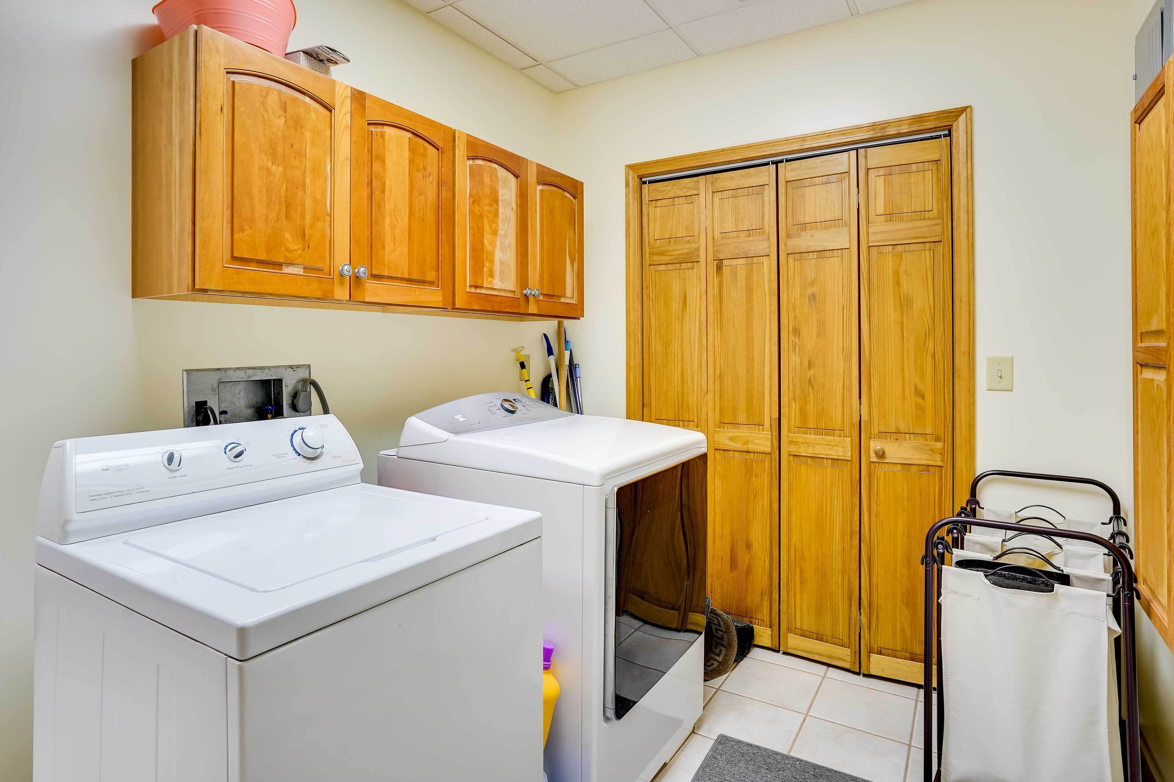 Une buanderie avec deux machines à laver blanches, des placards en bois au-dessus et une porte en bois.
