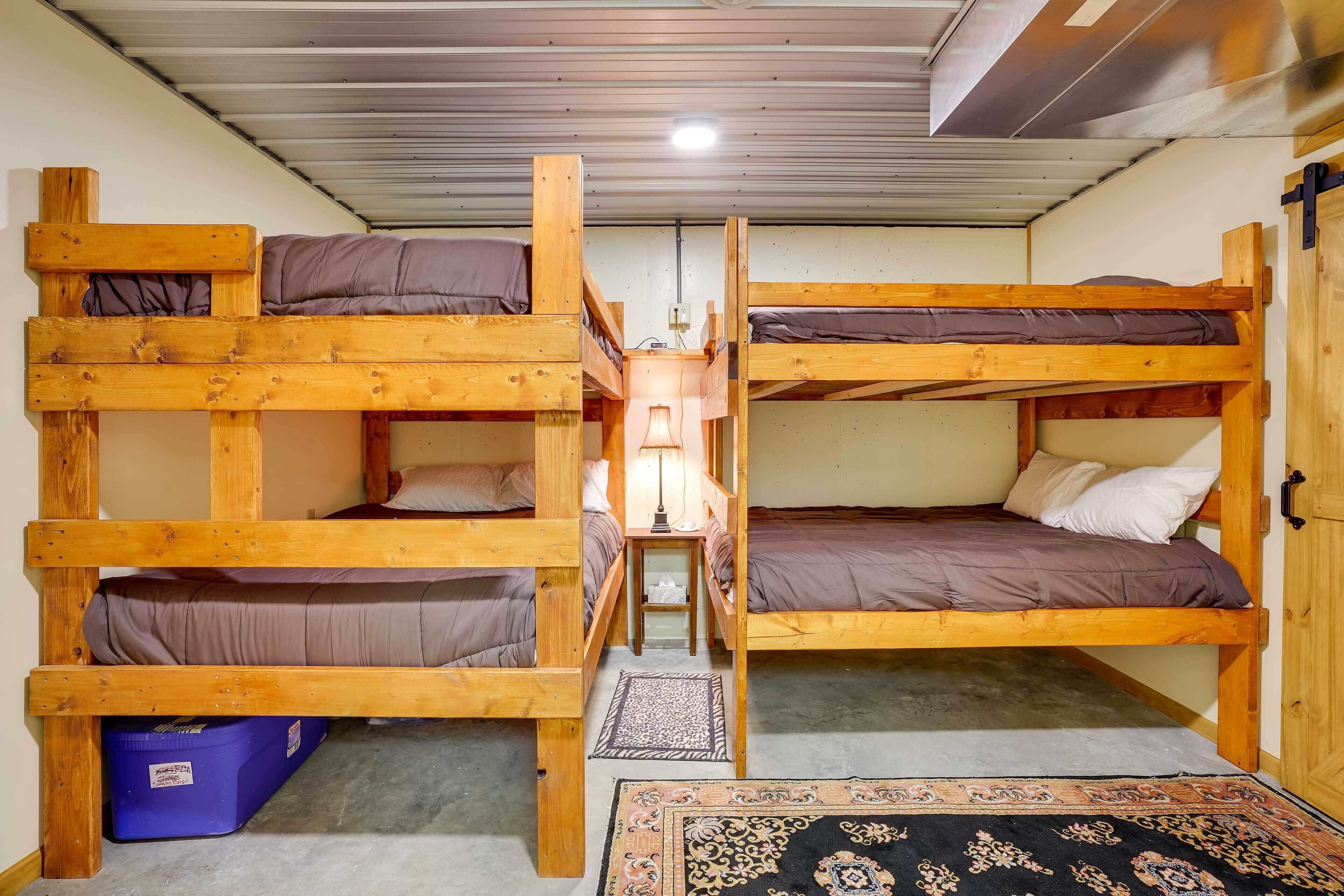A bunk bed room with two beds, a small table with a lamp, and a patterned rug on the floor.