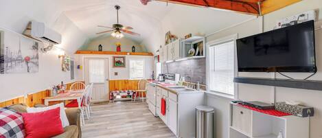 A cozy, well-lit kitchen with a dining area, wooden ceiling, and a TV mounted on the wall.