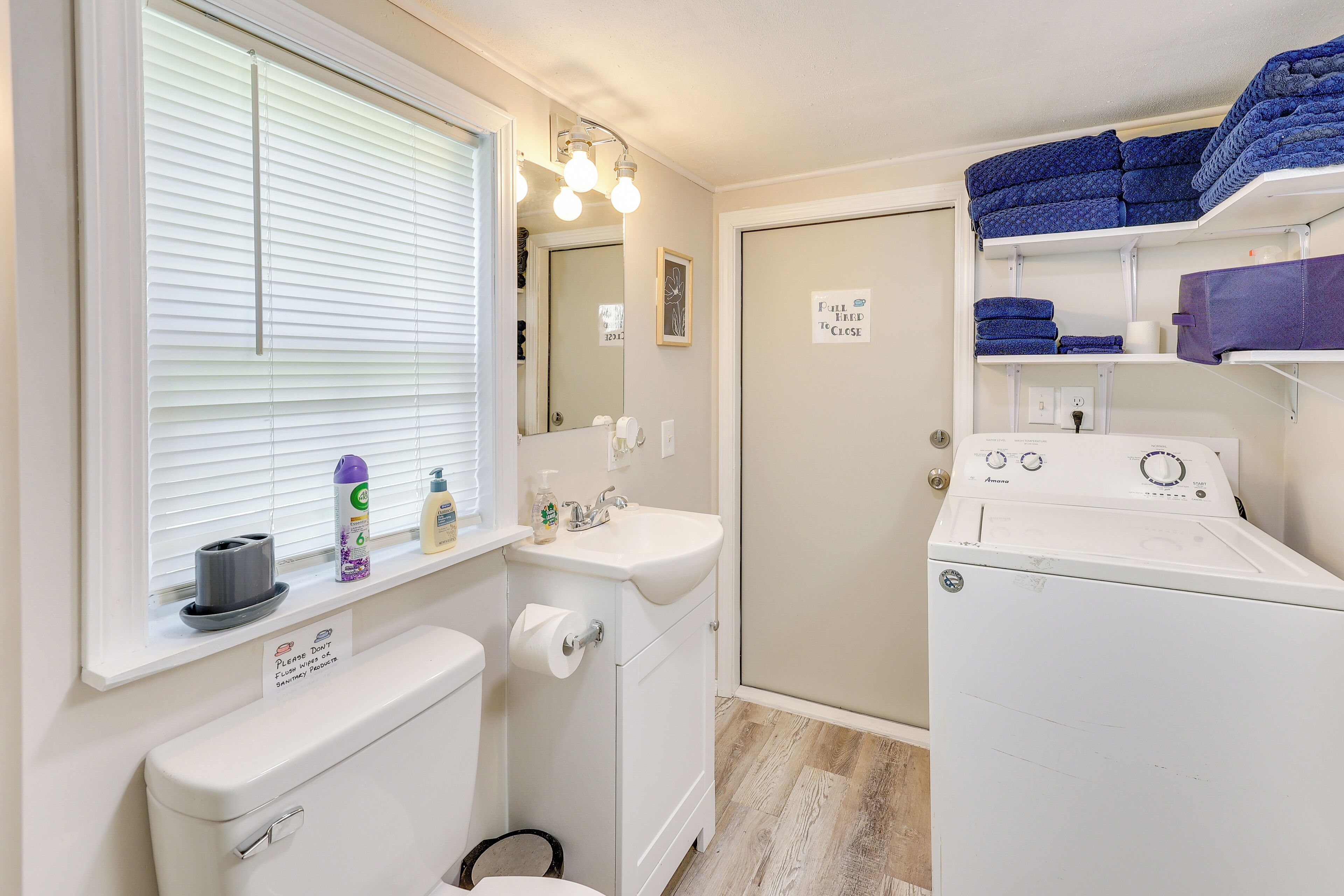 A compact laundry room with a washing machine, a sink, and a toilet.