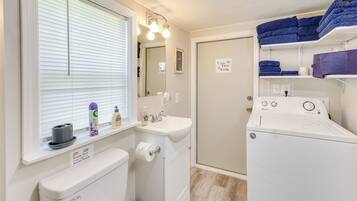 A compact laundry room with a washing machine, a sink, and a toilet.