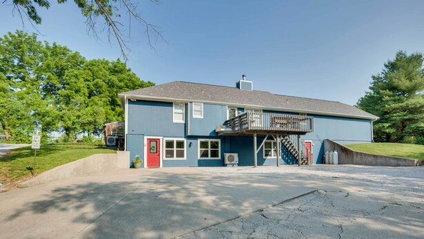 A two-story building with a blue exterior, a red door, and a balcony. - Missouri Studio Getaway: Close to Parks & Hiking (Liberty)