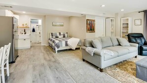 A modern living room with a sofa, a coffee table, and a dining area with a table and chairs. - Missouri Studio Getaway: Close to Parks & Hiking (Liberty)