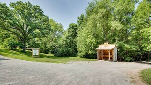 A gravel driveway leading to a wooden cabin surrounded by dense trees. - Missouri Studio Getaway: Close to Parks & Hiking (Liberty)