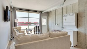 Un salon avec un canapé, un fauteuil, une petite table et un lave-linge.