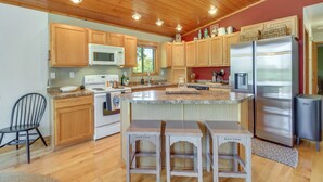 A kitchen with wooden cabinets, a stainless steel refrigerator, a microwave, and a sink.