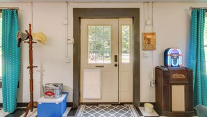 A hotel entrance with a door, a coat rack, a bucket, a jukebox, and teal curtains. - Killen Vacation Rental: Walk to Wilson Lake! (Killen)