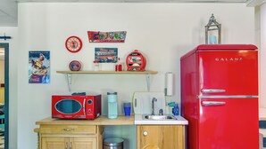 A compact kitchen with a red Galanz refrigerator, a microwave, a coffee maker, and vintage Coca-Cola memorabilia. - Killen Vacation Rental: Walk to Wilson Lake! (Killen)