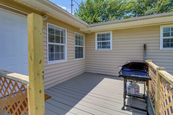 A covered patio area with a barbecue grill and propane tank, wooden deck, and a white door. - Charming Kaw Lake Country Home w/ Game Room! (Newkirk)