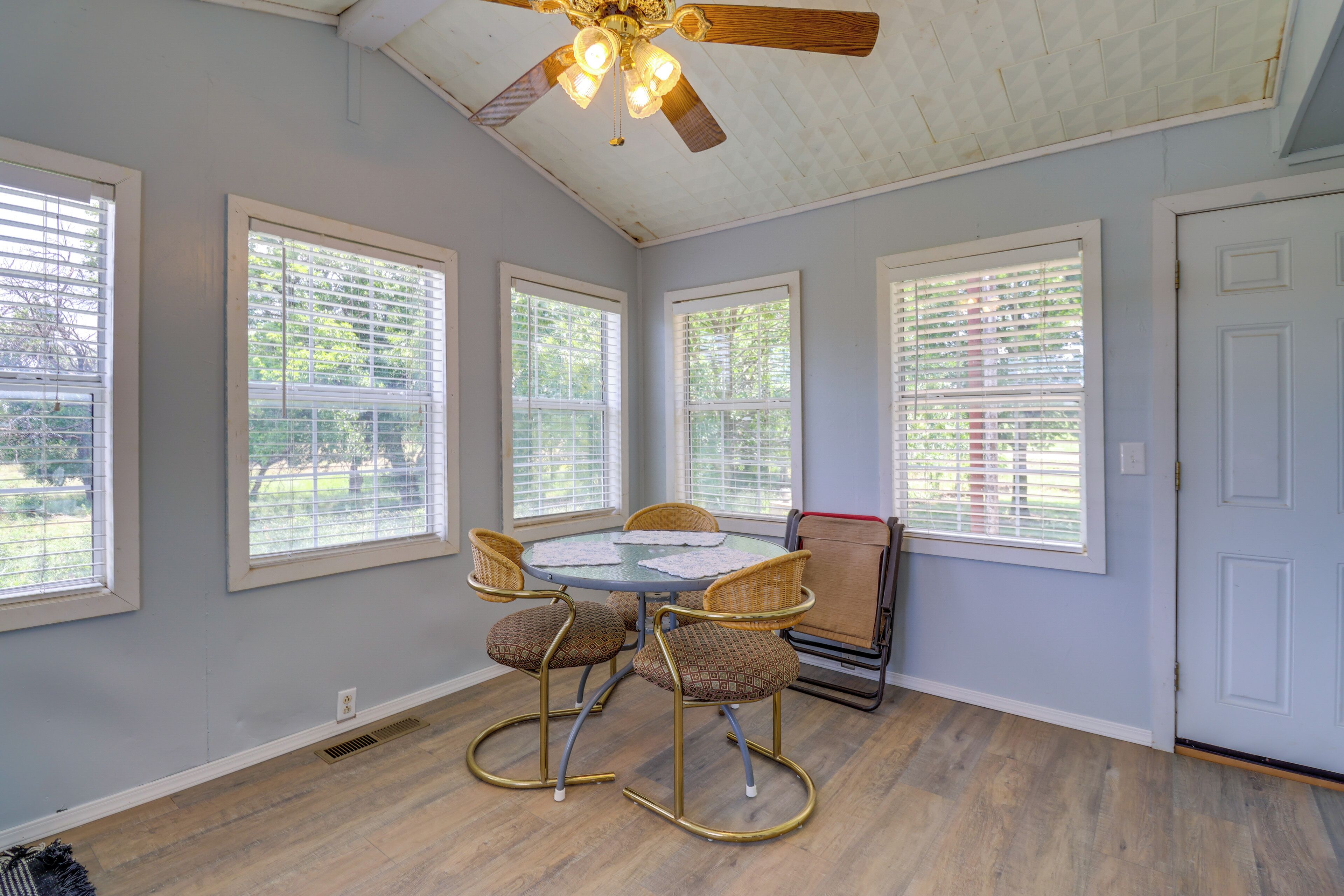 A dining area with a round table, four chairs, and a ceiling fan.