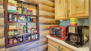 Une cuisine rustique, située dans une cabane en bois, équipée d’un porte-épices, d’une machine à café et d’un four à micro-ondes.