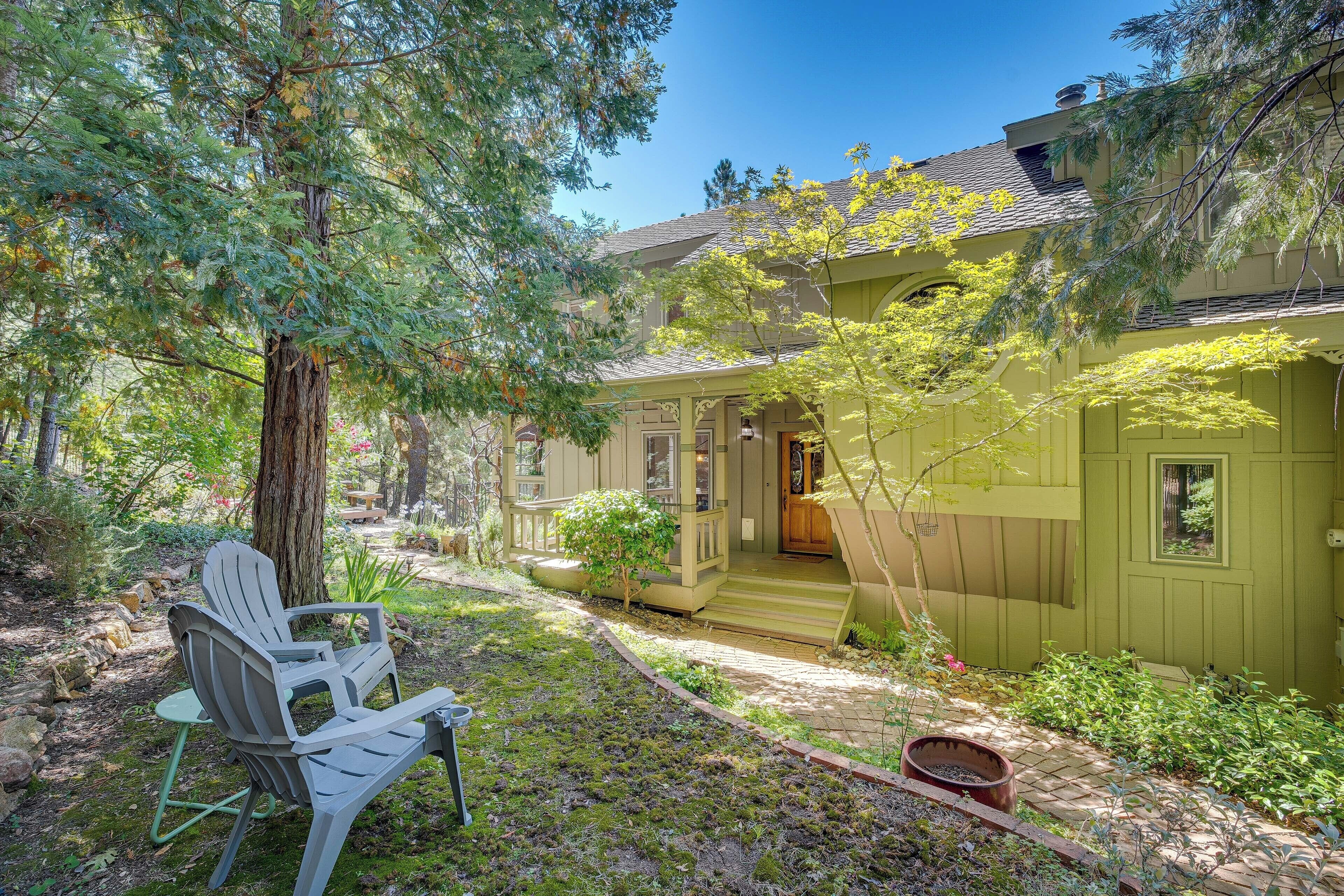 A house with a porch, a garden with a bench, and a tree.
