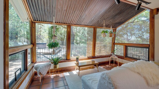 Ein geräumiges Zimmer mit großen Fenstern, einer Holzbalkendecke und einem gemütlichen Bett mit einer weißen, flauschigen Decke.
