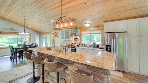 A spacious kitchen with a large island, bar stools, and a stainless steel refrigerator.