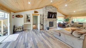 A spacious living area with a stone fireplace, wooden flooring, and a cozy couch.