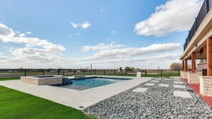 A backyard with a swimming pool, a stone patio, and a fenced area. - The Oasis Ranch 20-acre Ranch in Whitewright! (Whitewright)