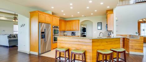 A spacious kitchen with wooden cabinets, stainless steel appliances, and a central island with bar stools.