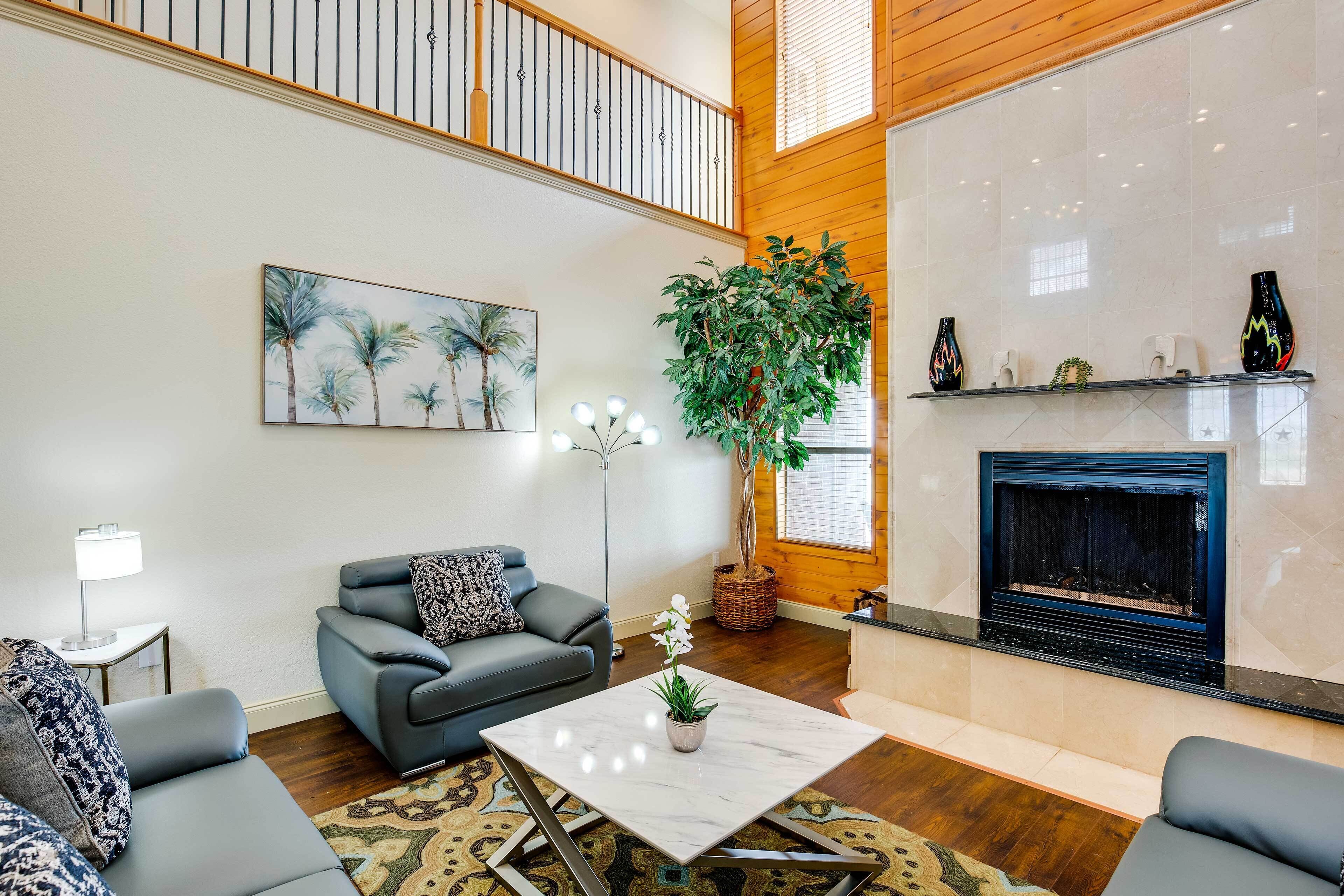 Una sala de estar con chimenea, una planta grande en maceta y un conjunto de sofás modernos.