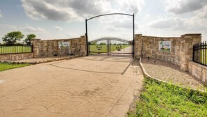 A gated entrance with stone walls and a paved pathway leading to a grassy area. - The Oasis Ranch 20-acre Ranch in Whitewright! (Whitewright)
