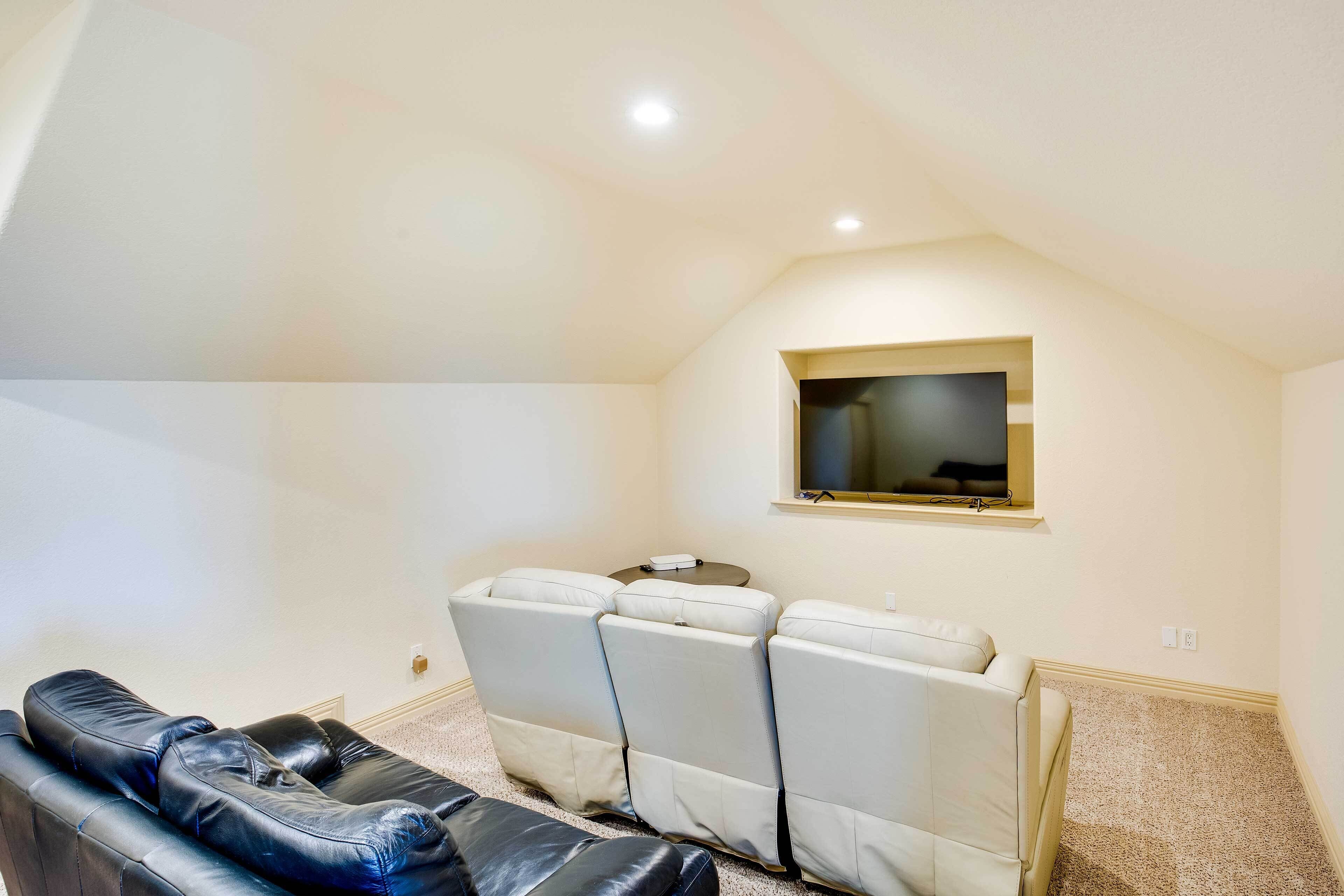 A home theater room with a large screen, reclining chairs, and carpeted flooring.