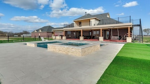 A two-story house with a large patio, a swimming pool, and a covered outdoor seating area. - The Oasis Ranch 20-acre Ranch in Whitewright! (Whitewright)