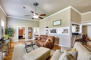 A spacious living room with a brown leather sofa, a beige couch, and a dining area with wooden chairs.