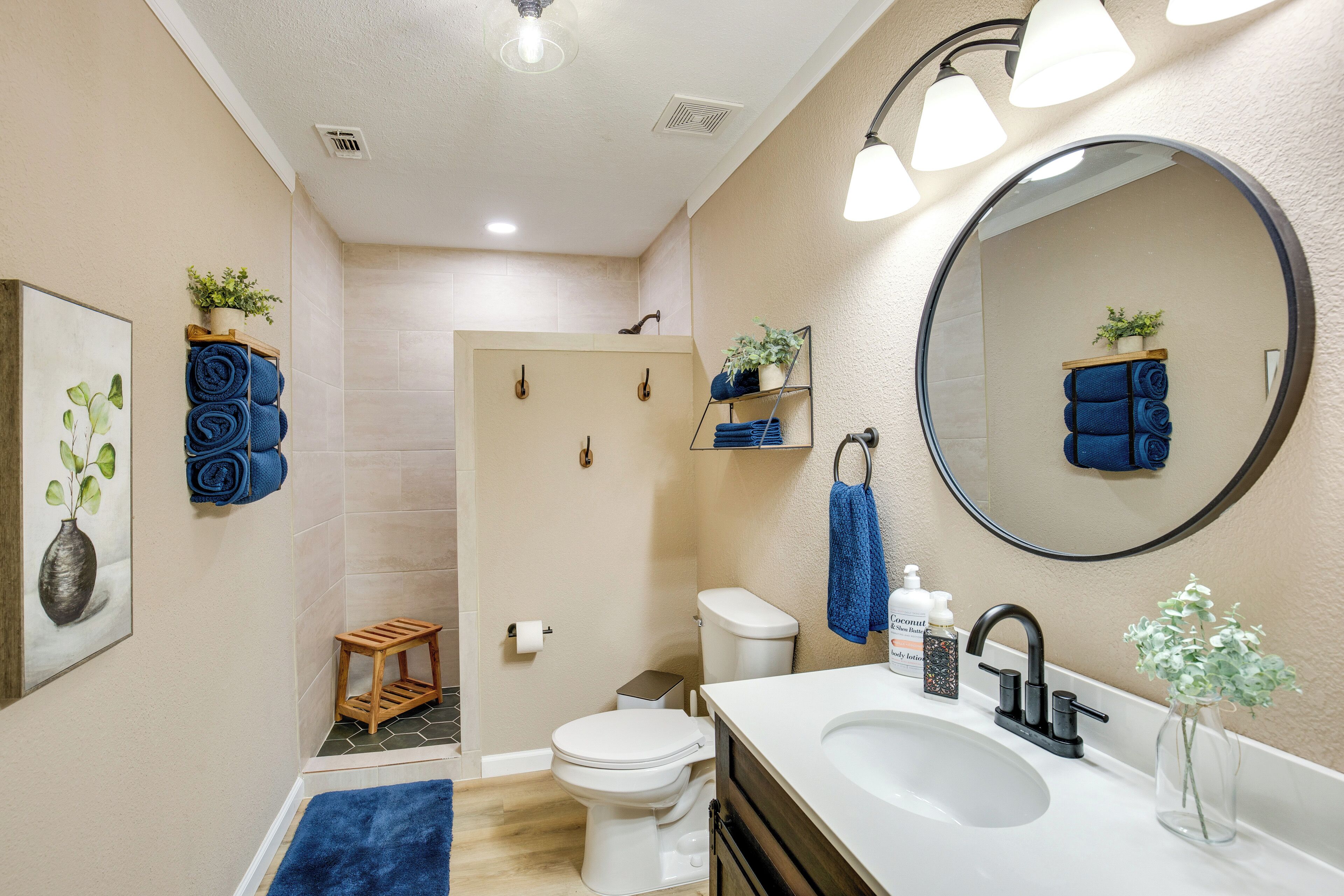 A bathroom with a white sink, a large mirror, and a toilet. There are towels and toiletries on the counter.