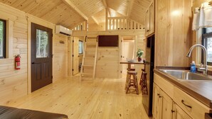 Ein Holzblockhaus-Innenraum mit Küchenzeile, Esstisch und Feuerlöscher.