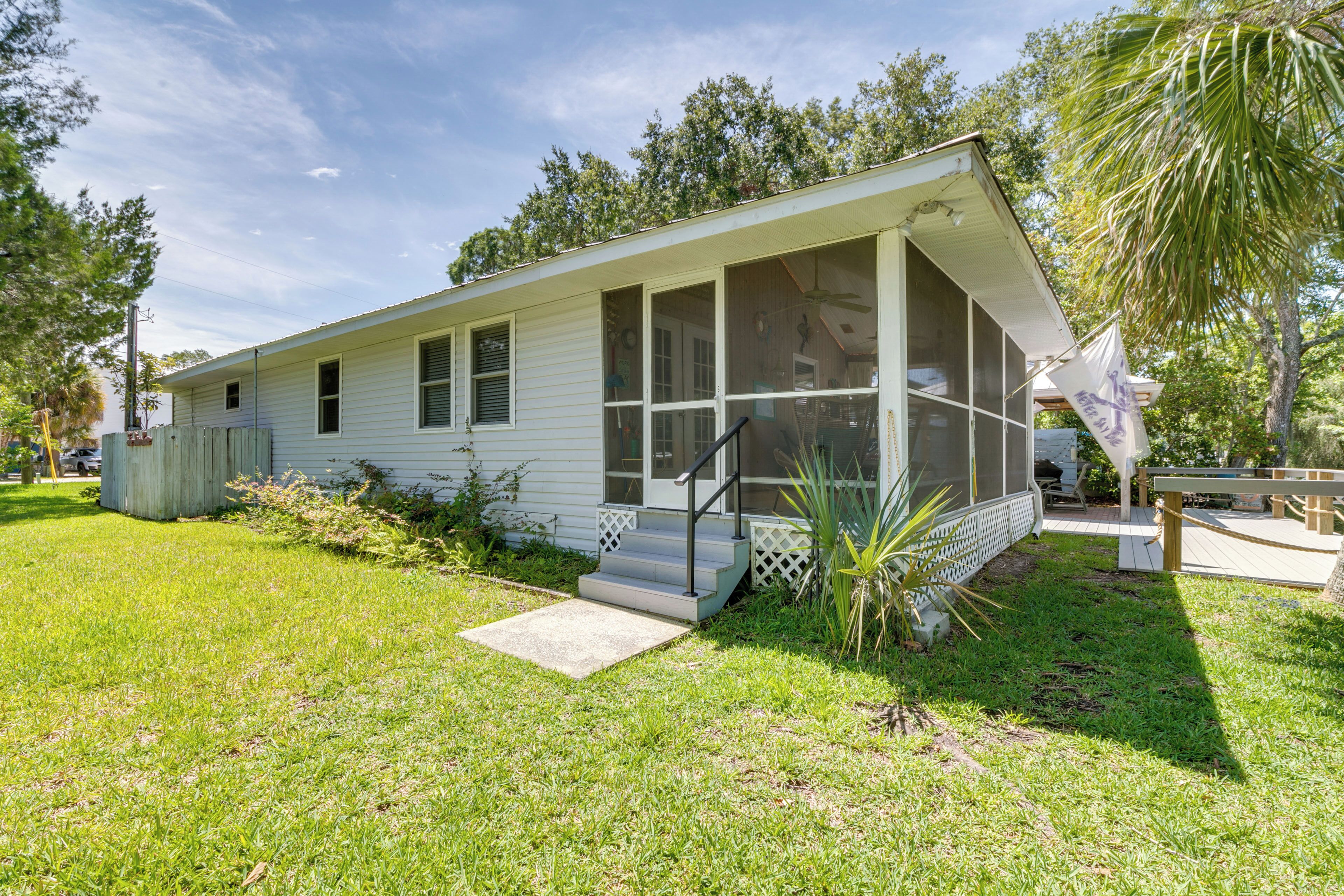 A single-story house with a porch, a small front yard, and a palm tree.