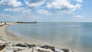 A beach with calm waters, a sandy shore, and scattered rocks. - Hot Tub Haven 2 Mi to Beach! Christy's Cottage (Snow Hill)