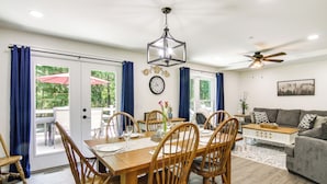 A dining area with a wooden table and chairs, a clock on the wall, and a ceiling fan. - Hot Tub Haven 2 Mi to Beach! Christy's Cottage (Snow Hill)