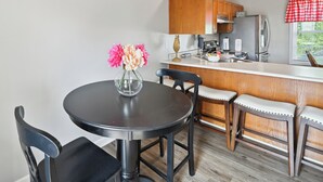 Une cuisine compacte dotée de meubles en bois, d’un réfrigérateur en acier inoxydable et d’un coin bar avec des tabourets.