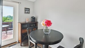 Un coin repas comprenant une table ronde, des chaises, une machine à café et un vase de fleurs.