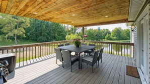 A wooden deck with a table and chairs, overlooking a lake and surrounded by trees. - 'heaven on the Hill' Retreat w/ Deck + Gas Grill! (Frewsburg)